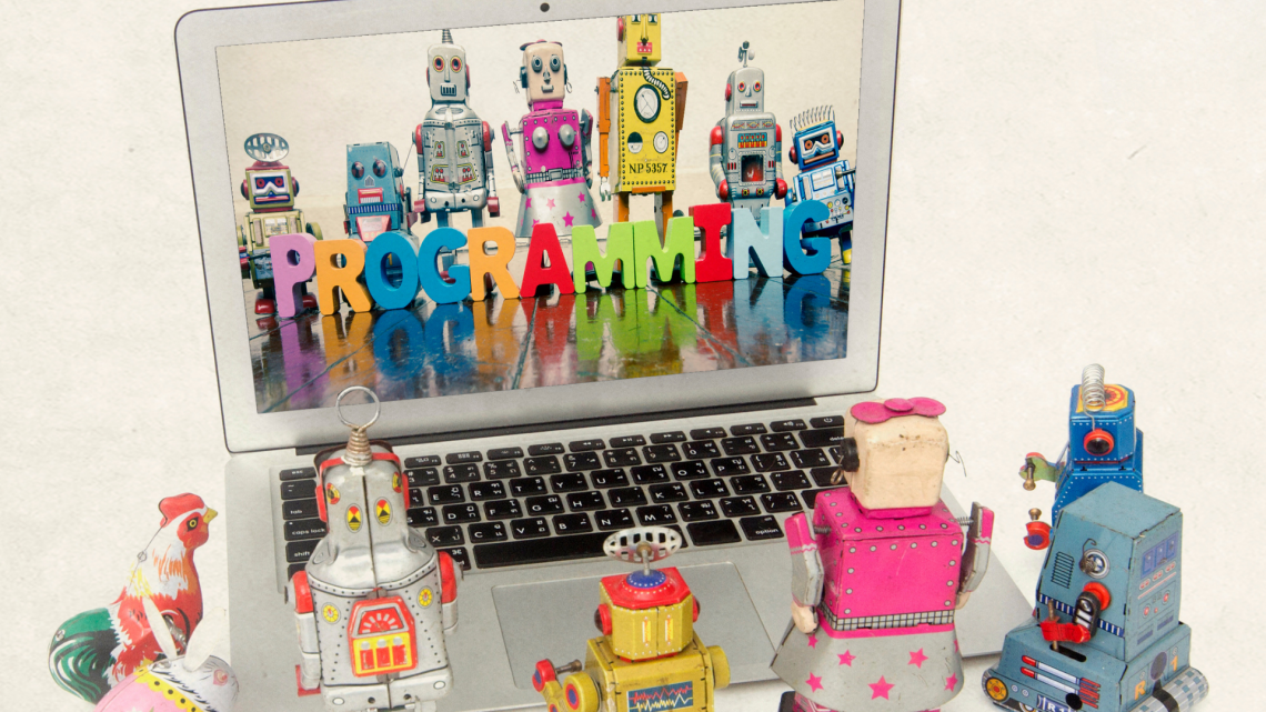 little robots surrounding computer that reads programming
