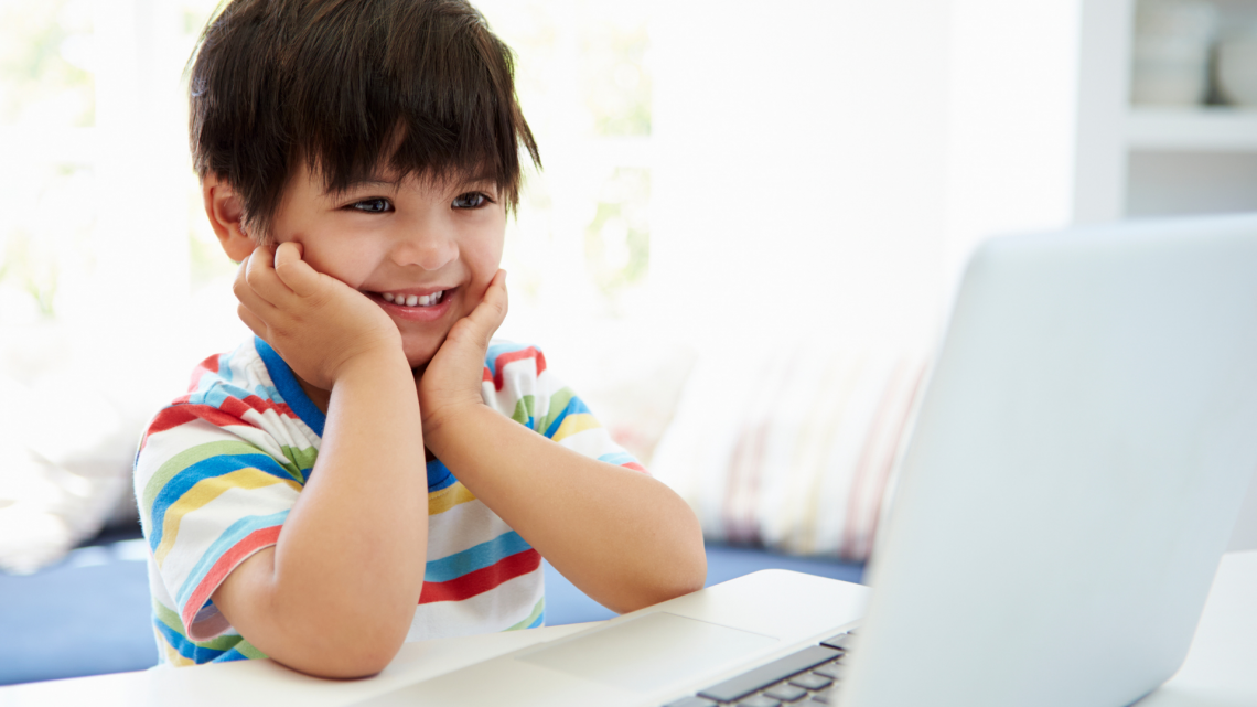 kid smiling in front of laptop