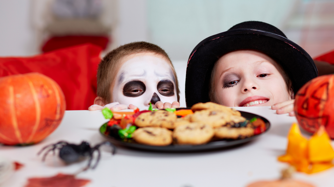 kids in halloween costumes looking at cookies