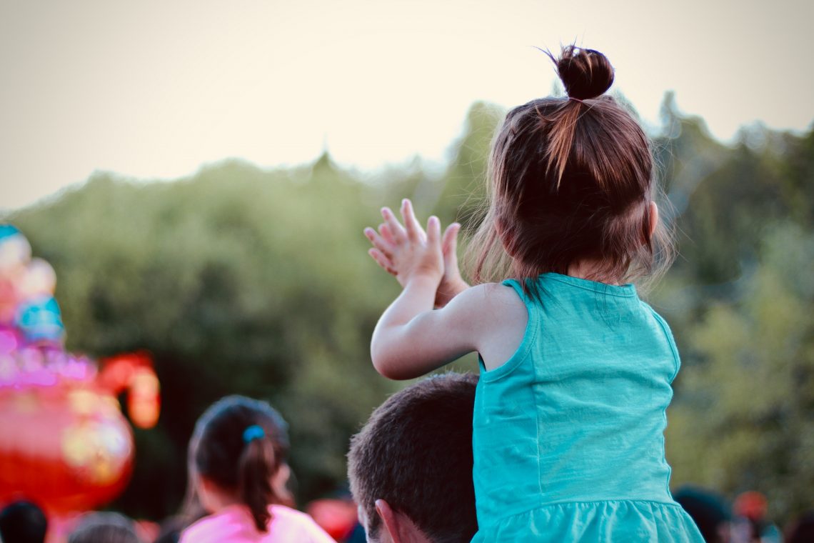 kid on parent's shoulders at outdoor event